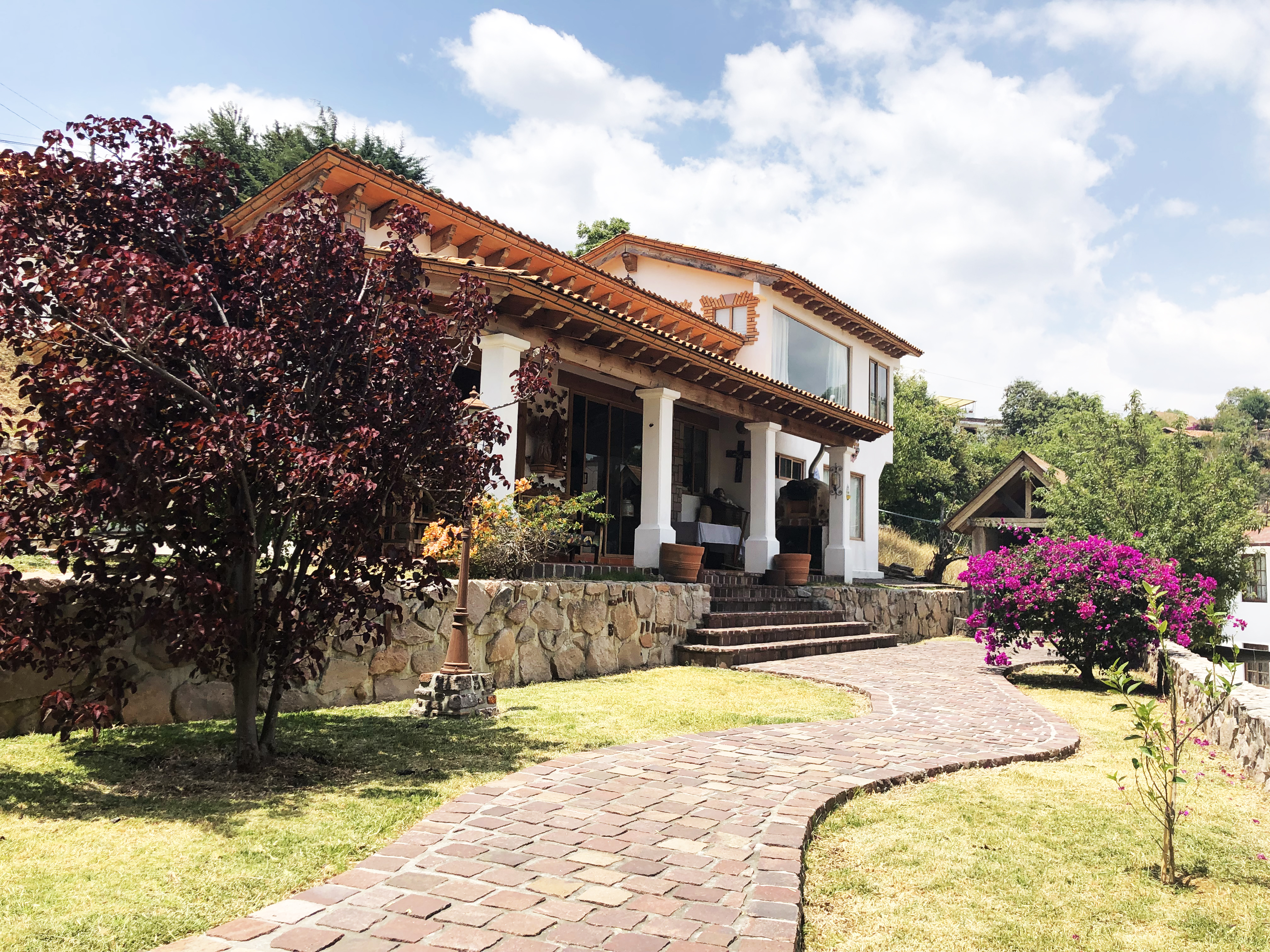 Vista exterior del Refugio "Casas" con jardín, andador curvo y pórtico principal